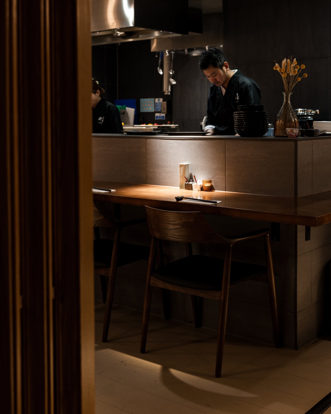 A counter seat view at Hotori — the yakitori chef working over the binchotan grill, seen from a guest's perspective