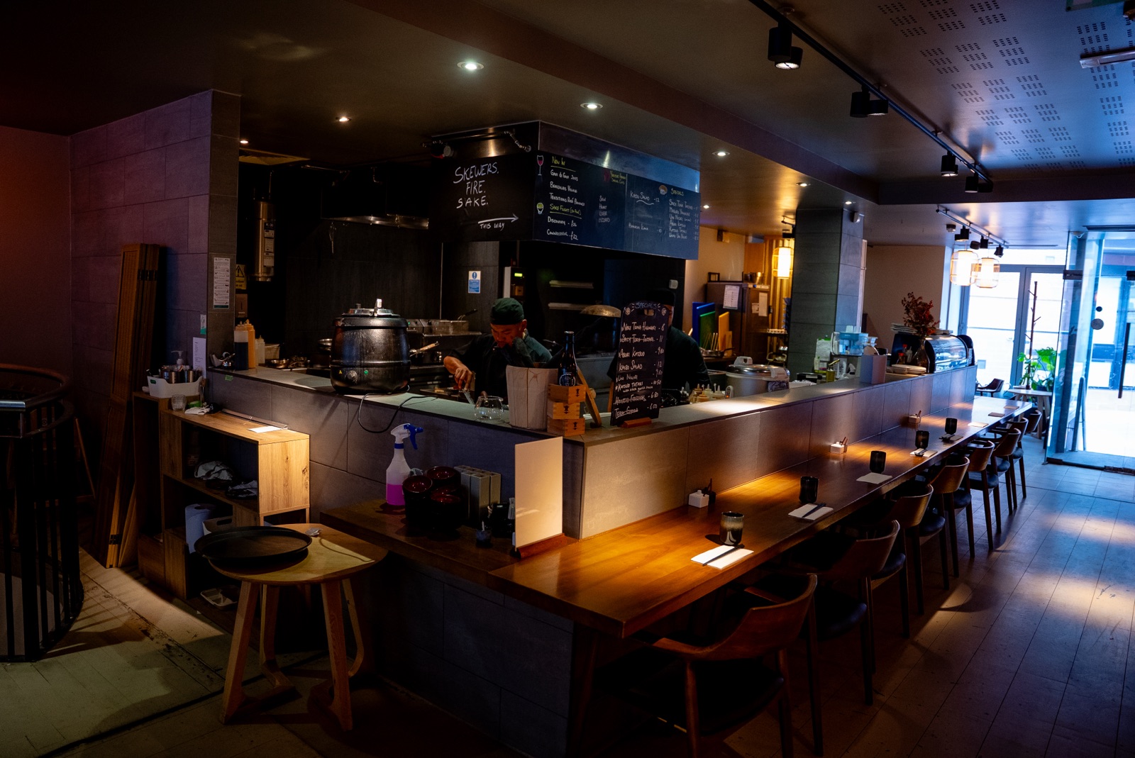 The counter at Hotori — eight stools facing the open kitchen, lit for the evening