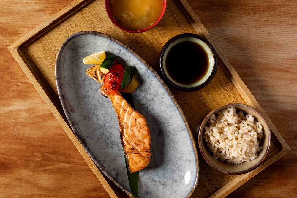 A lunch set on a wooden tray — grilled salmon teriyaki, miso soup, rice and tare
